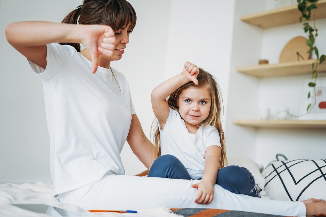 woman-looking-daughter-showing-thumbs-down